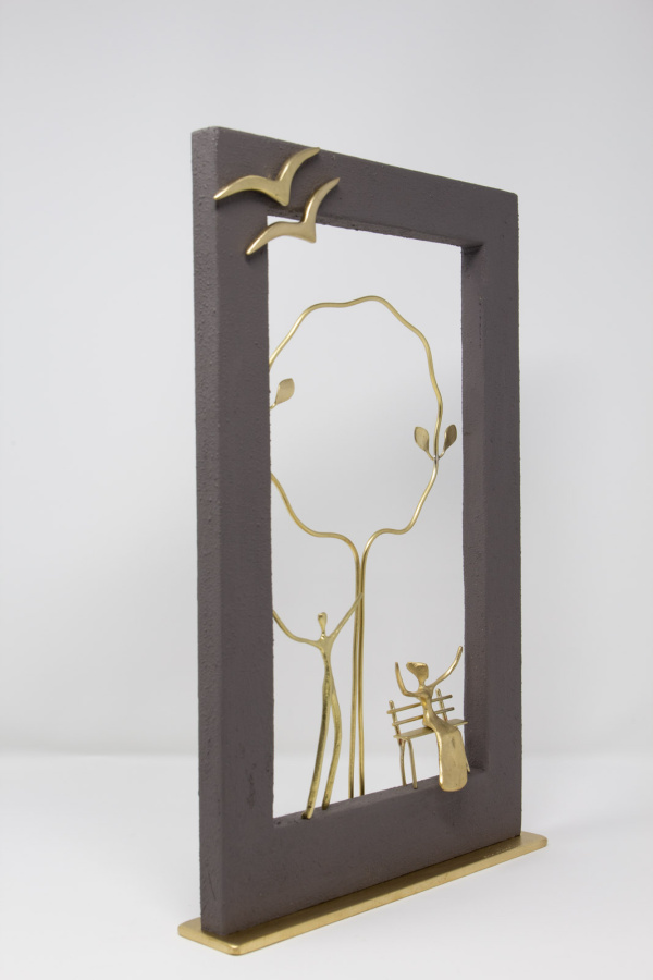 Limited Edition hand made bronze sculpture featuring a couple in the park her sitting on a bench with her arms up celebrating and a lovely dark frame framing the scene with a couple of birds flying over by Anna Andreadi