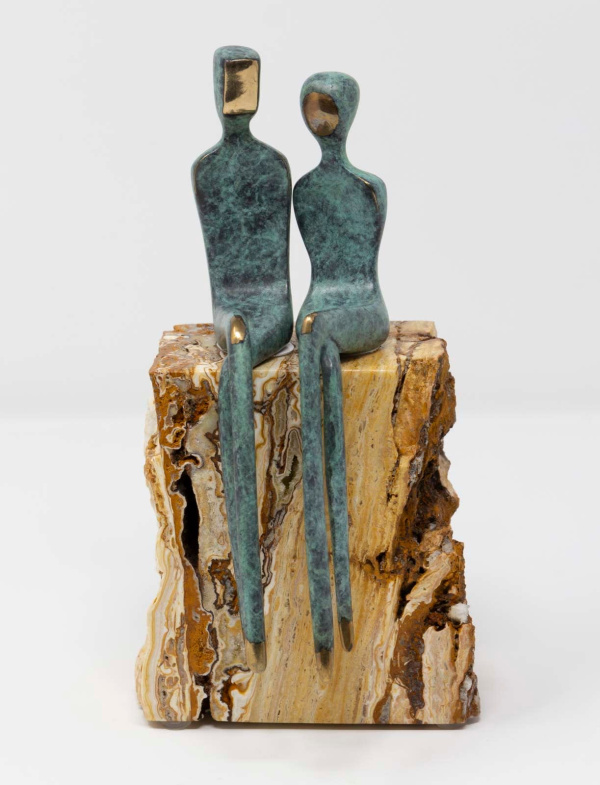 bronze sculpture on a travertine marble base by artist Yenny Cocq with two minimalist style figures in a green patina sitting atop the stone